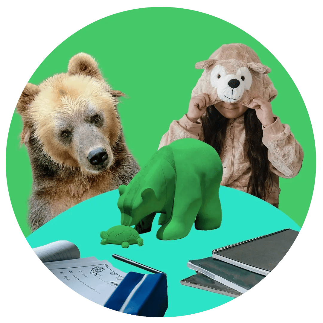 A big brown bear and a girl in a bear costume are looking at a school table, where a wooden bear is looking at a wooden turtle.